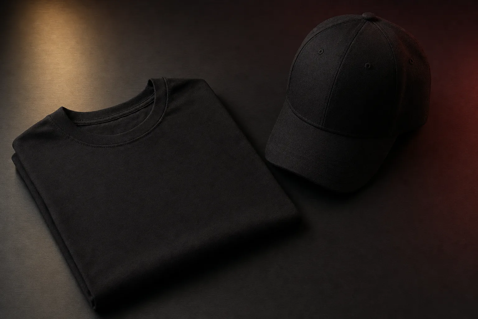 Folded black t-shirt and structured black cap, preview of upcoming branded apparel line